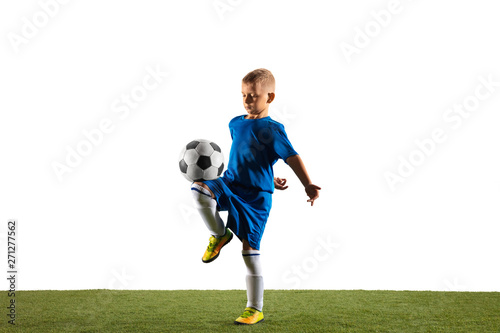 Young boy as a soccer or football player in sportwear making a feint or a kick with the ball for a goal on white studio background. Fit playing boy in action, movement, motion at game. photo