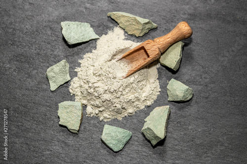 Zeolite natural  raw stones and powder on black stone  background.Selective focus photo