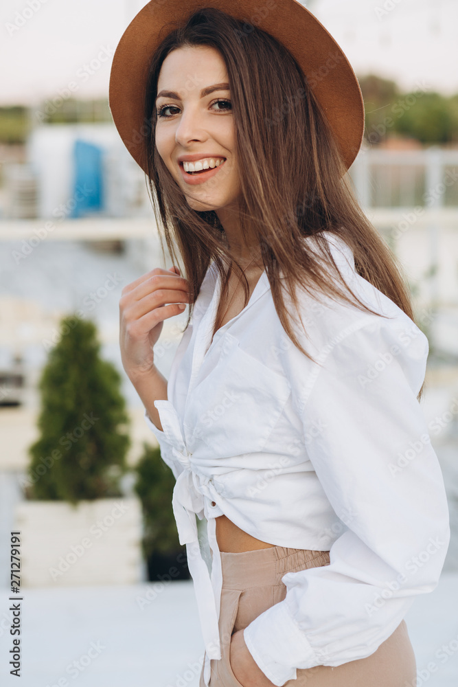A happy stylish woman walks along the beachfront on a warm summer day in the sunset A happy stylish woman walks along the beachfront on a warm summer day in the sunset
