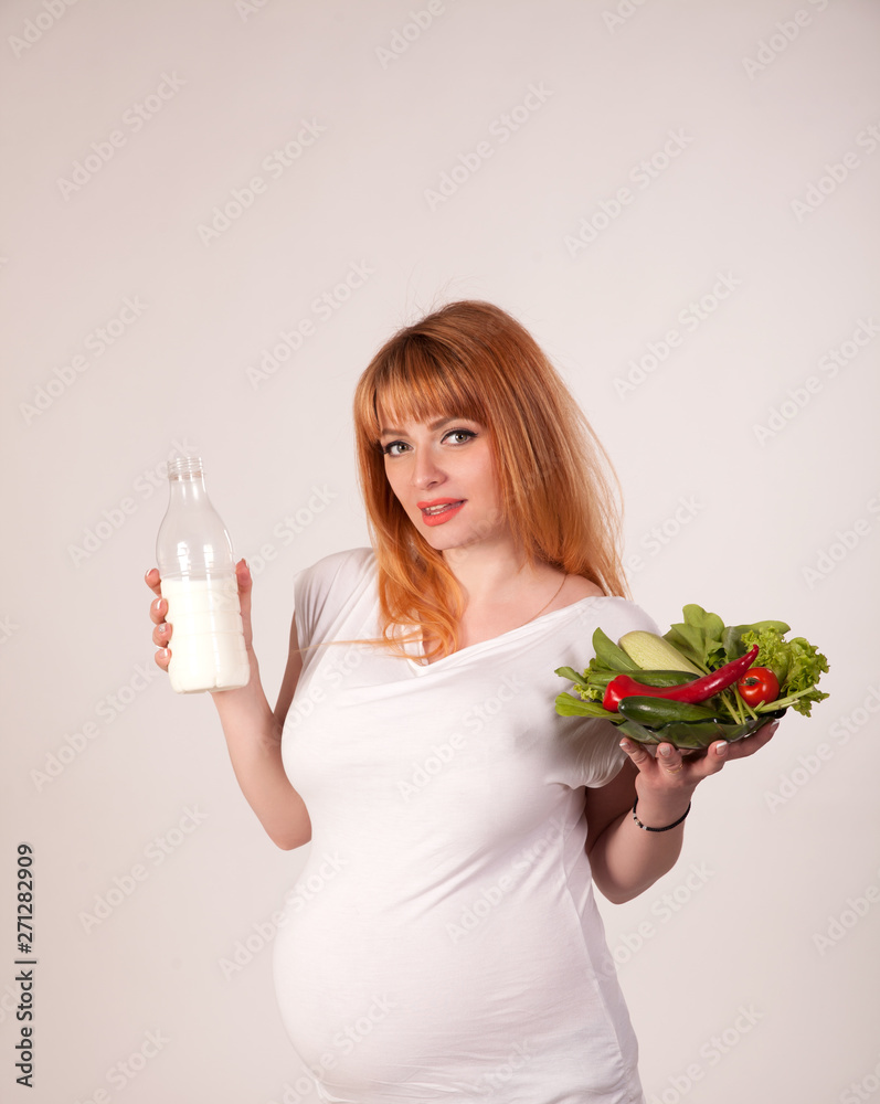 Beautiful pregnant woman with vegetables in her hands and a bottle of milk. Healthy nutrition during pregnancy. Beautiful pregnant woman with vegetables in her hands and a bottle of milk. Healthy nutrition during pregnancy.