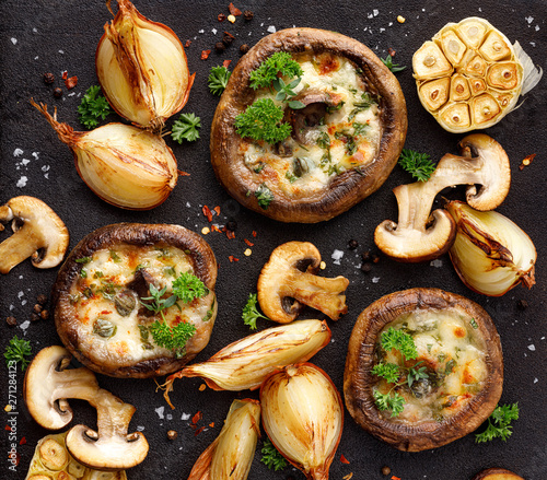 Canvas Print Stuffed portobello mushrooms stuffed with mozzarella and gorgonzola cheese and aromatic herbs on a black background, top view