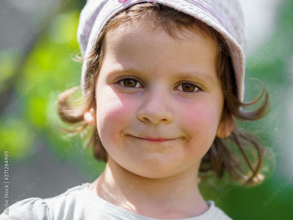 Portrait of a small caucasian girl with a hat protecting from the harsh sun. Green blur background. Portrait of a small caucasian girl with a hat protecting from the harsh sun. Green blur background.