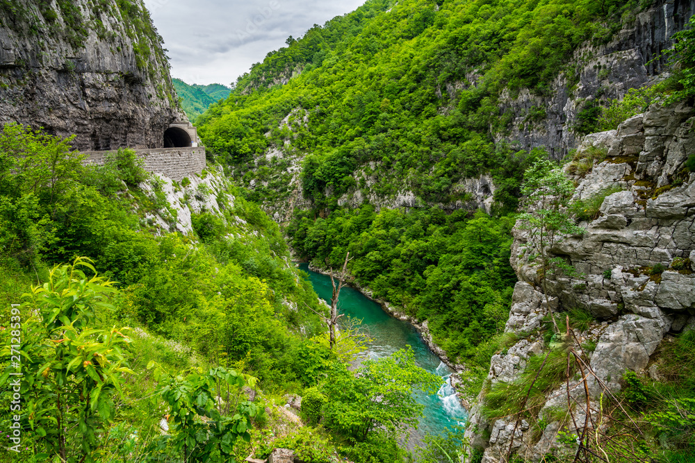 Montenegro, Road leading traffic through tunnel in moraca canyon next to beautiful turquoise waters of moraca river