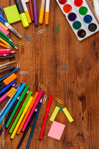colorful pencils, markers and pens composition mock-up Back to school concept with stationery office supplies on a brown wooden background with copy space top view
