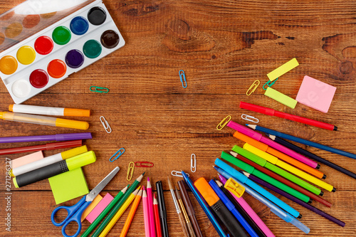 colorful pencils, markers and pens composition mock-up Back to school concept with stationery office supplies on a brown wooden background with copy space top view