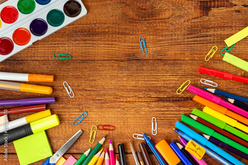 colorful pencils, markers and pens composition mock-up Back to school concept with stationery office supplies on a brown wooden background with copy space top view