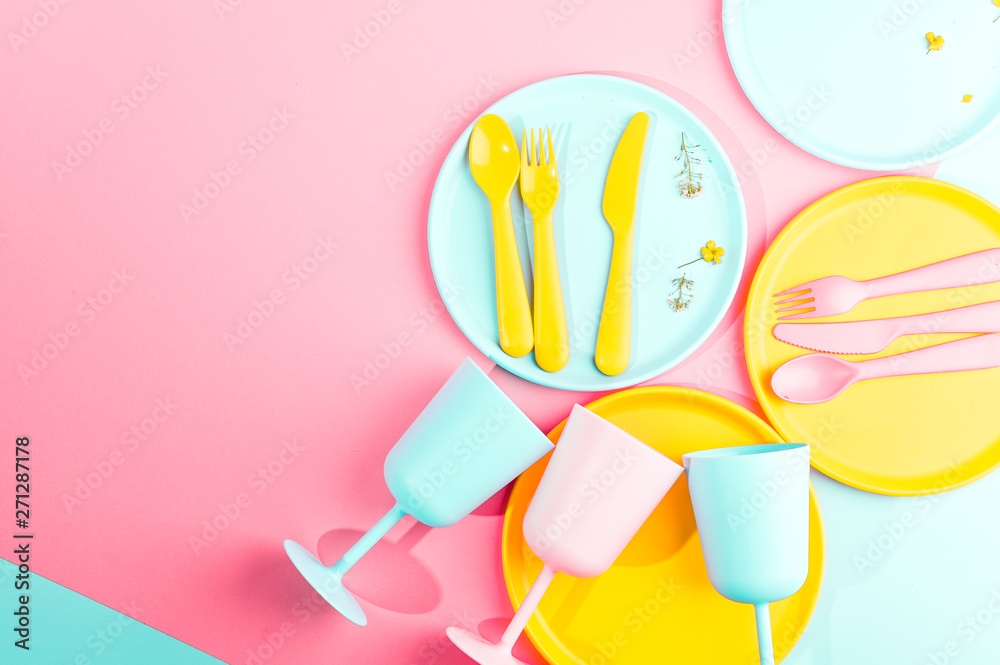 Bright colored plastic picnic utensils. Pink, yellow, blue colors in the bowl. Photo in hard light. Copy space Bright colored plastic picnic utensils. Pink, yellow, blue colors in the bowl. Photo in hard light. Copy space