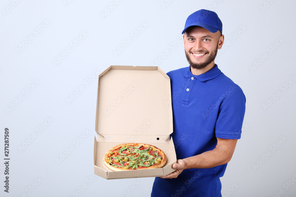 Delivery man with pizza in cardboard box on grey background Delivery man with pizza in cardboard box on grey background