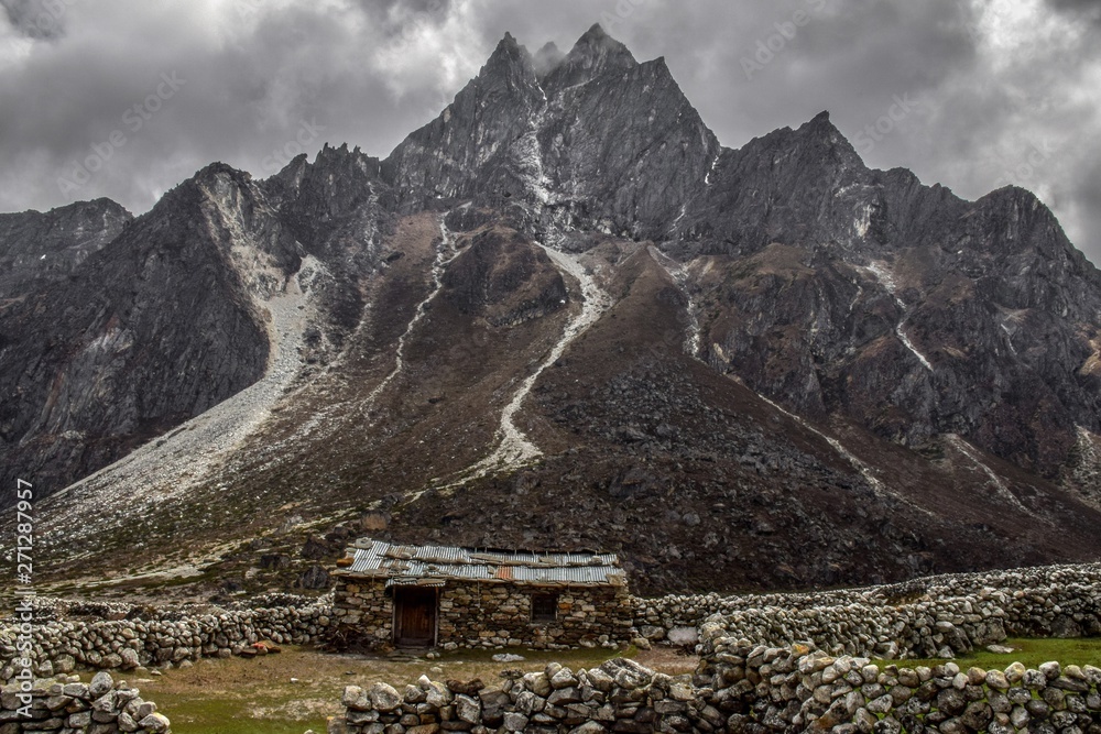 Stone house alone in front with several big mountains on background