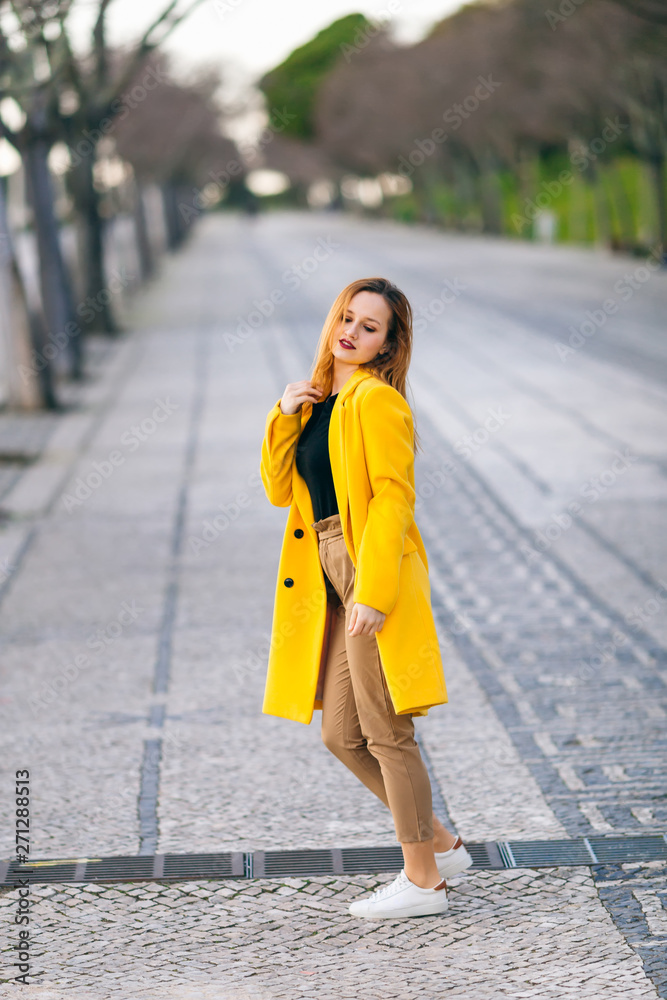 portrait of a girl in a yellow coat walking in street. Female fa portrait of a girl in a yellow coat walking in street. Female fa