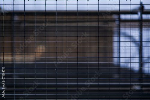 Background or texture in the blue sky of a crossbeam from building lattices. View of balconies from below. Cage, grid, wire.