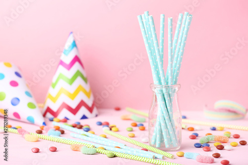 Paper straws in glass jar with candies on pink background