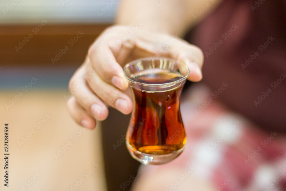 Turkish man holds out black Turkish tea in a traditional glass Turkish man holds out black Turkish tea in a traditional glass