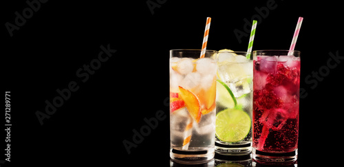 Delicious summer  lemonades with ice,berry, peach and lime on black background. Three glass with cold, fresh drink or coctail on black table