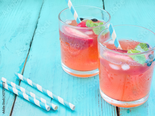 Delicious summer  lemonades with ice,berry, peach and lime on wooden background. Two glass with cold, fresh drink or coctail on blue table