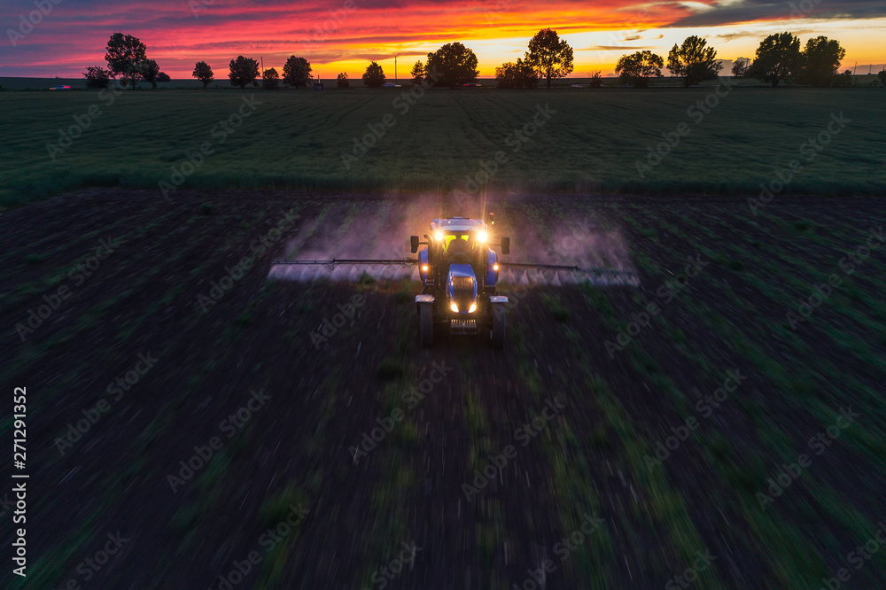 Fototapeta premium Tractor spraying field at spring