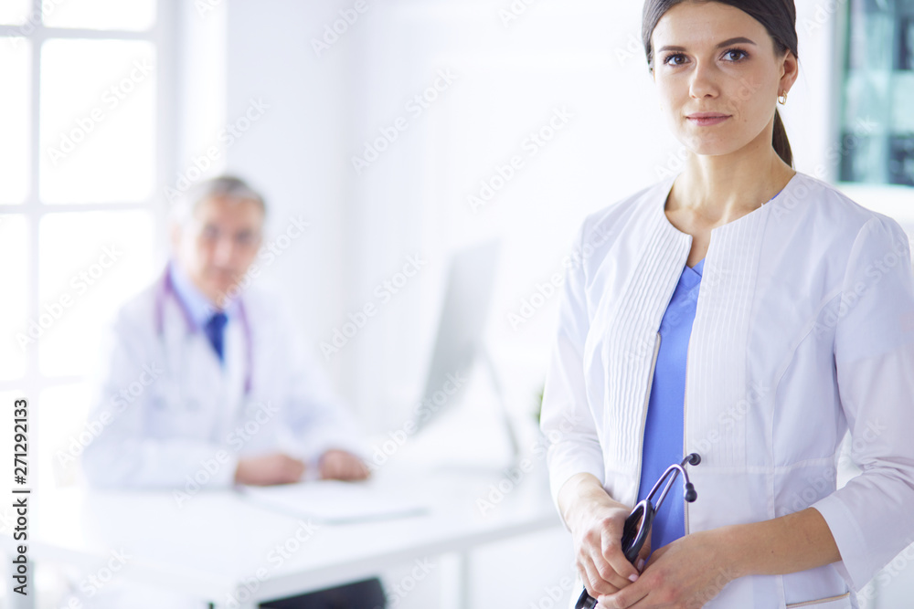 A doctor looking at the camera with her male colleage in the back of the conference room in hospital