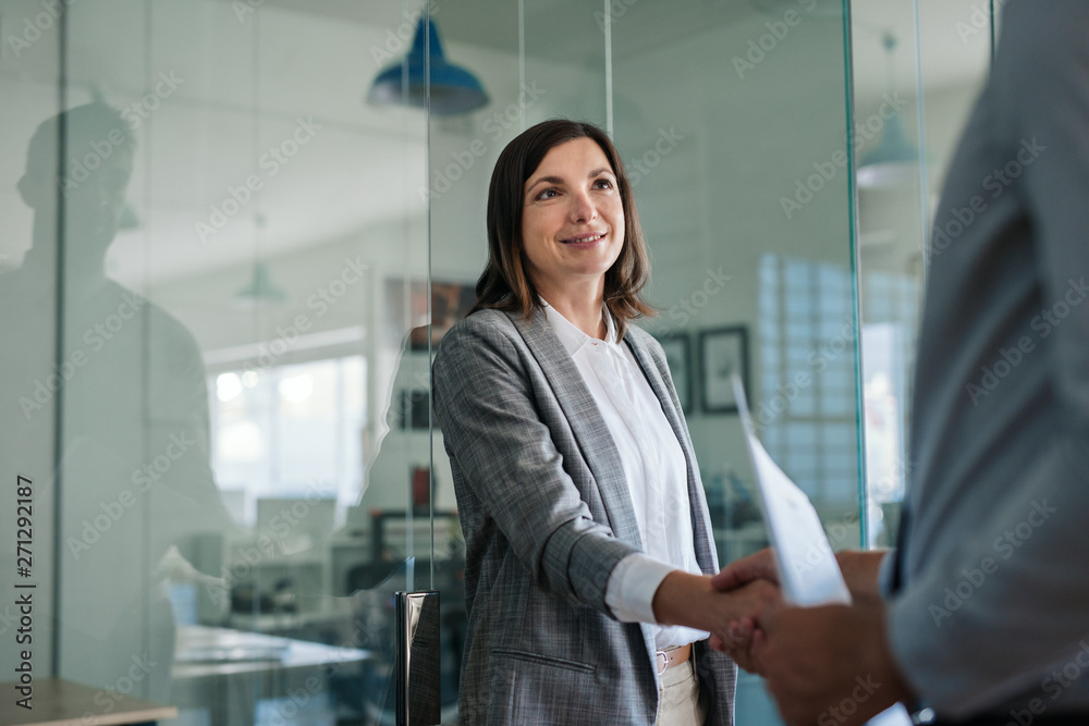 Businesswoman shaking hands with a new employee in an office Businesswoman shaking hands with a new employee in an office
