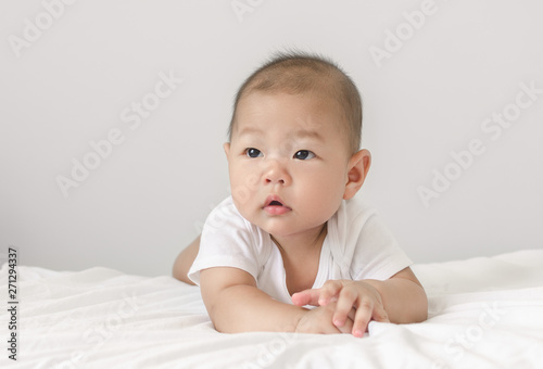 portrait of little small asian baby infant laying on bed looking up