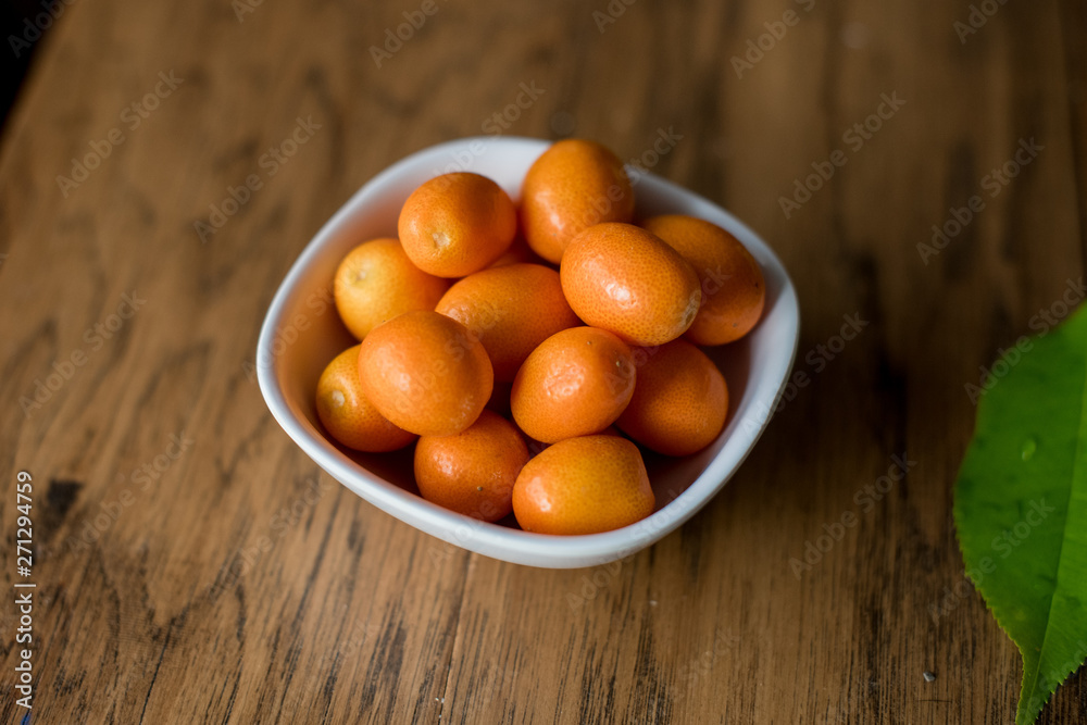 Wood table with bowl of kumquats Wood table with bowl of kumquats