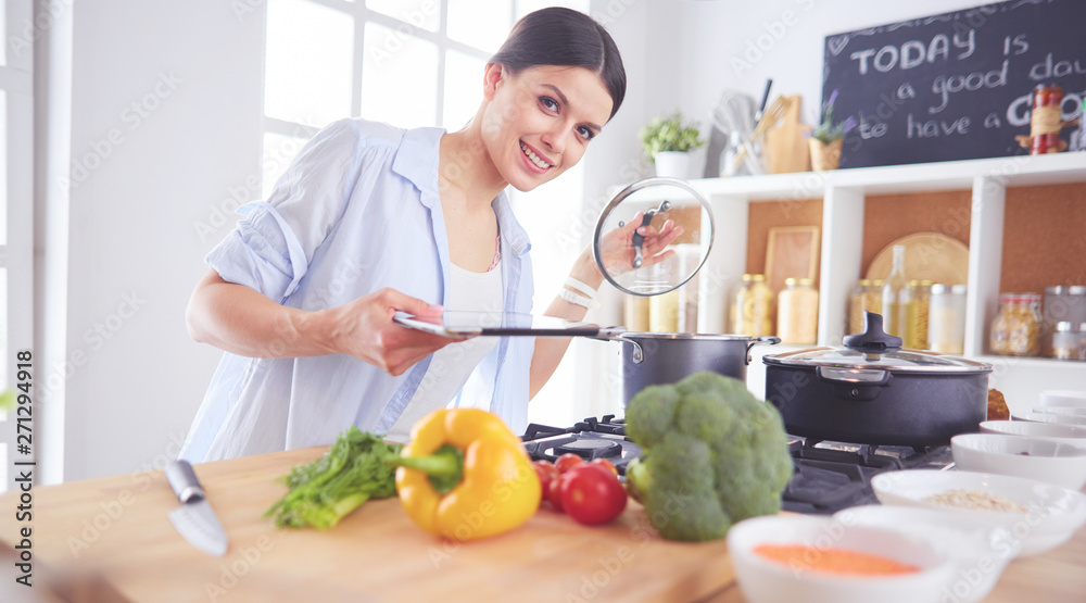 Young woman standing by the stove in the kitchen Young woman standing by the stove in the kitchen