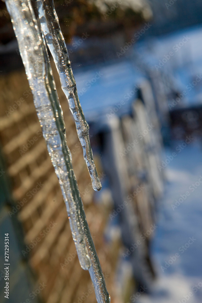 Winter in the Netherlands. Icicle hanging from a reed roof of a farmhouse. Melting ice. Winter in the Netherlands. Icicle hanging from a reed roof of a farmhouse. Melting ice.