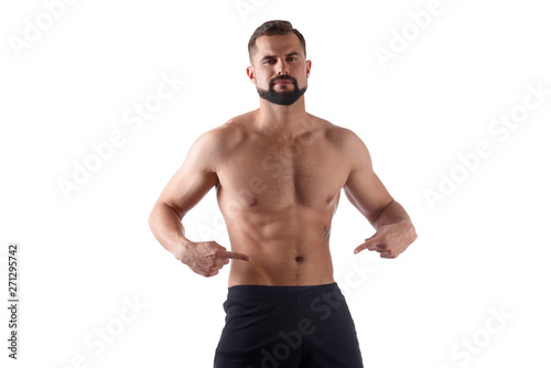 Athlete with a strong torso shows fingers on the cubes on his stomach. Muscular man shows his abs, isolated on white background