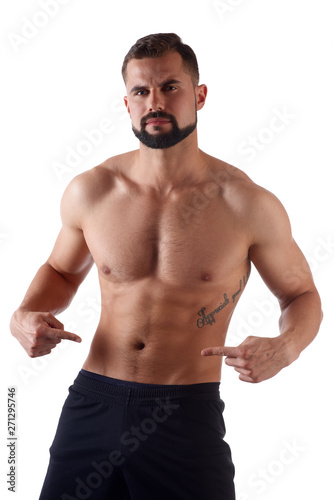 Athlete with a strong torso shows fingers on the cubes on his stomach. Muscular man shows his abs, isolated on white background