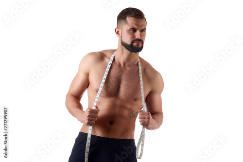 Muscular young man with measuring tape. Sportsman holds measure on isolated white background. Sport and healthy concept