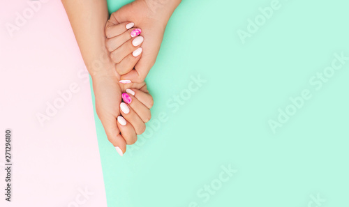 Top view of perfect manicure with trendy nail art on pink and turqoise background
