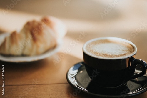 cup of coffee and croissant on wooden table