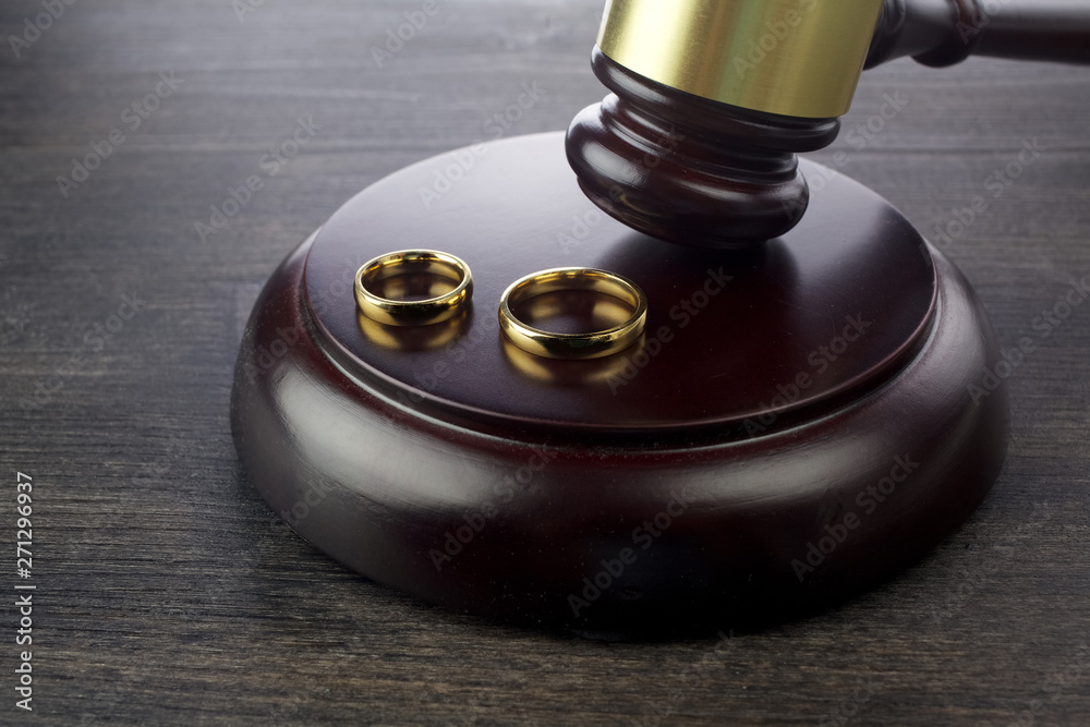 Wedding rings hammer of a judge on a dark wooden background. Divorce proceedings Wedding rings hammer of a judge on a dark wooden background. Divorce proceedings