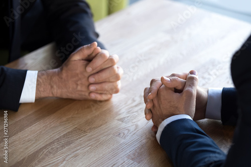 Close up of businessmen sit with hands clenched making decision