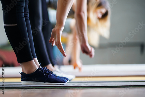Flexibility, activity, yoga, pilates, warming up concept. Women hands stretching to toecaps on group workout © Vadym