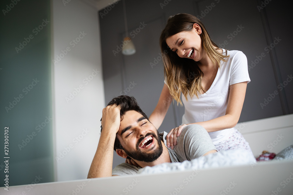 Obraz premium Young woman is doing her handsome boyfriend massage and smiling while they are resting at home