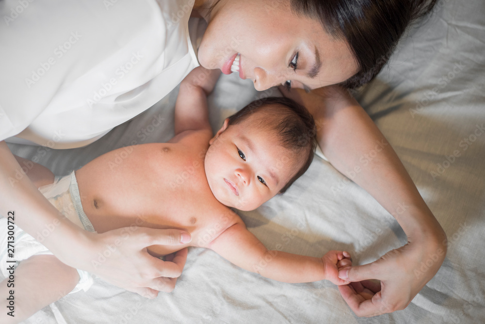 Beautiful mother is playing with her newborn baby in the bedroom. Beautiful mother is playing with her newborn baby in the bedroom.
