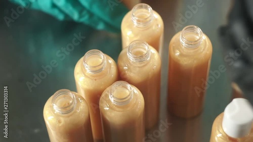 Production of cosmetics. Laboratory assistants taking a bottle of shampoo and closing it up