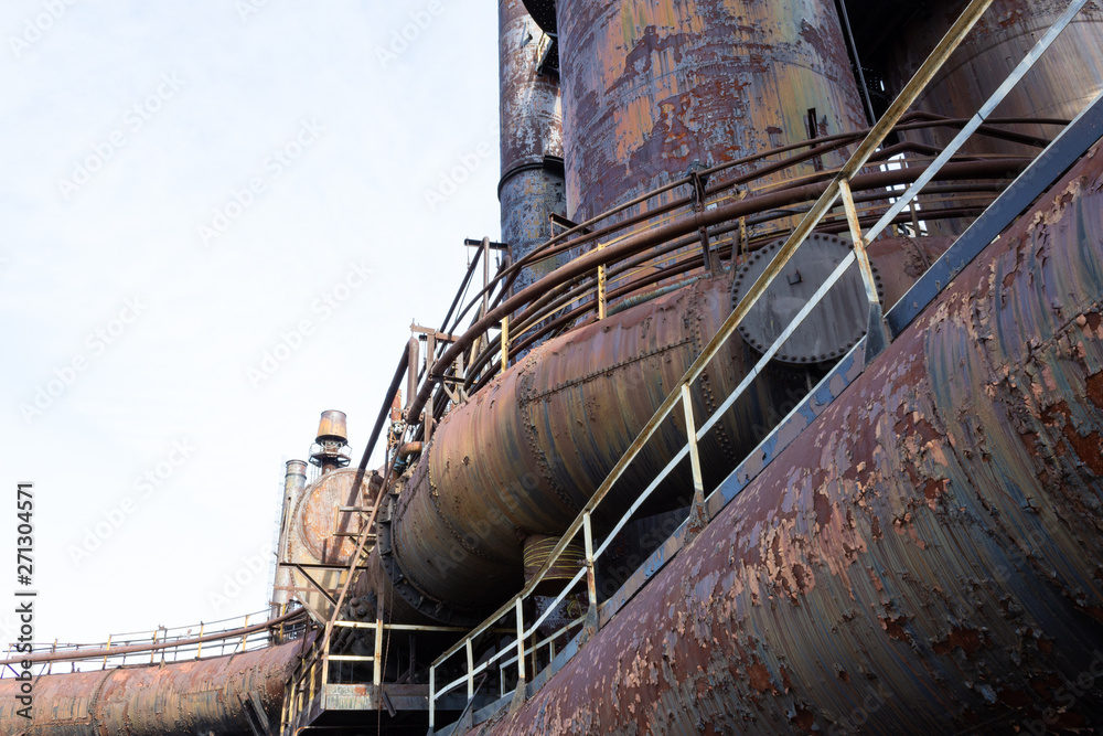 Curved industrial pipes and tubes of old steel mill with heavy patina of rust, copy space, horizontal aspect Curved industrial pipes and tubes of old steel mill with heavy patina of rust, copy space, horizontal aspect