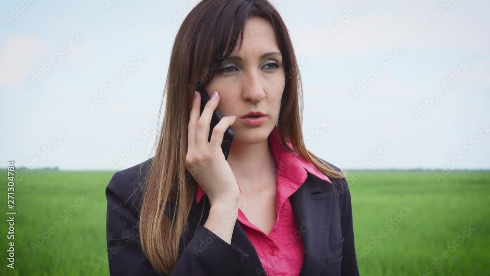 Woman with mobile phone makes order of fertilizers from sales manager of agricultural goods and walking through field with green barley. Business female on agricultural land Woman with mobile phone makes order of fertilizers from sales manager of agricultural goods and walking through field with green barley. Business female on agricultural land