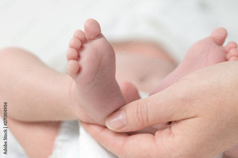 Closeup view of mother's hand holding the feet of her newborn son. Closeup view of mother's hand holding the feet of her newborn son.