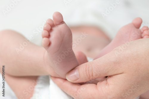 Closeup view of mother's hand holding the feet of her newborn son.