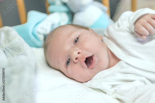Portrait of beautiful newborn boy lying in crib looking at the camera. 