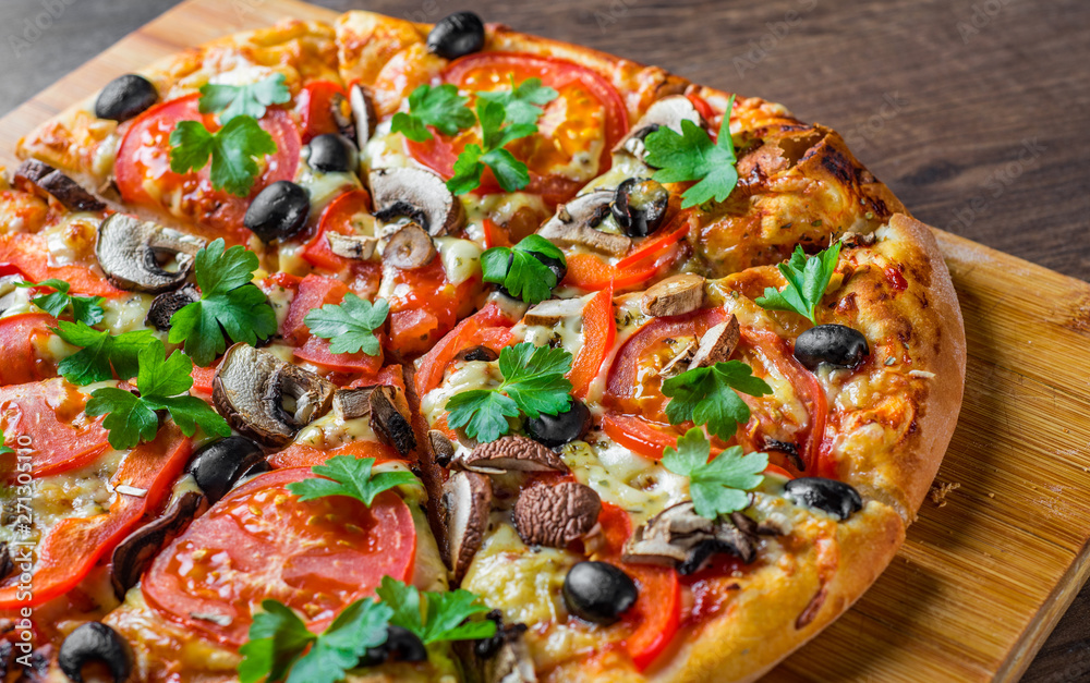 sliced Pizza with Mozzarella cheese, Tomatoes, pepper, olive, mushrooms, Spices and Fresh leaf. Italian pizza on wooden table background