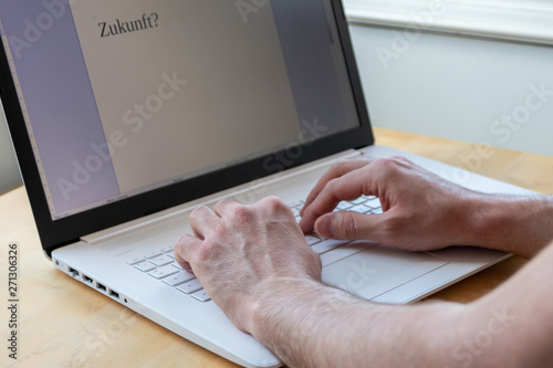 Mann schreibt am weißen Notebook das Wort Zukunft mit einer Textverarbeitung photo