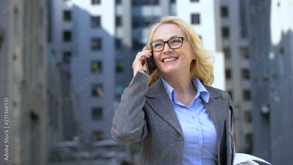 Successful business lady with documents in hand talking phone and smiling, work Successful business lady with documents in hand talking phone and smiling, work
