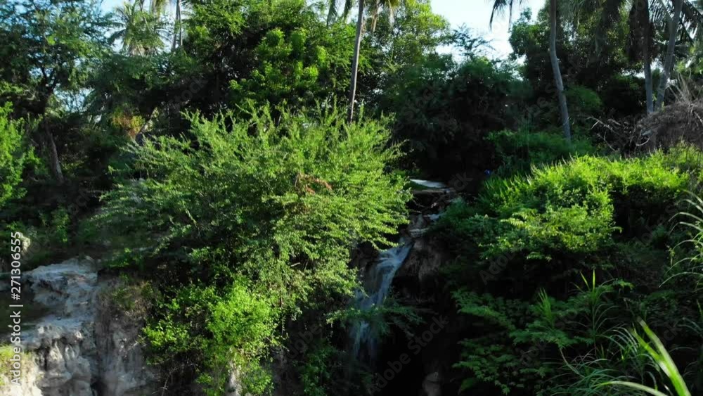 Aerial pull back, drone flying away from waterfall revealing park and palm trees. Aerial pull back, drone flying away from waterfall revealing park and palm trees.