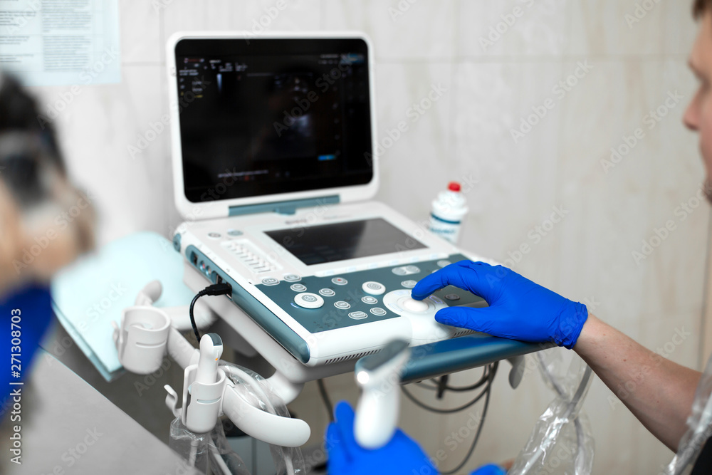 A veterinarian does an ultrasound of the dog's eye in the office. Male doctor's hand on an ultrasound machine close-up..Veterinary clinic background A veterinarian does an ultrasound of the dog's eye in the office. Male doctor's hand on an ultrasound machine close-up..Veterinary clinic background