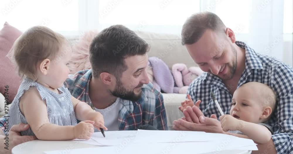 Two young fathers with baby girls studying together at home Two young fathers with baby girls studying together at home