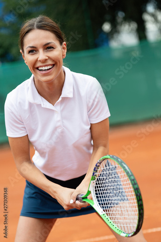 Young happy woman playing tennis at tennis court