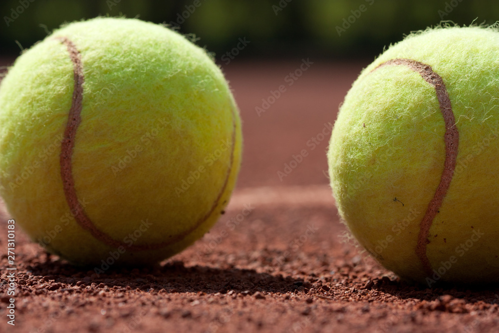 Close up of tennis balls on clay court.